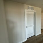 White louvered closet door in a beige-walled hallway